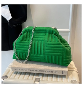 Close-up of bright green knitted shell bag with silver chain on books