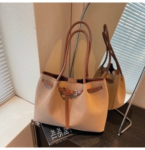 Close-up of khaki woven texture tote bag with dark brown handles and buckles