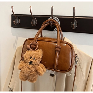 Detailed view of brown retro bowling bag with shiny PU leather and plush bear charm