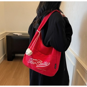 Detail of red canvas tote bag featuring white Tao Cai Tu embroidery and brand woven label