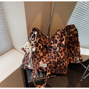 Detail of leopard print canvas tote bag featuring plush toast charm and pearl strap accessory
