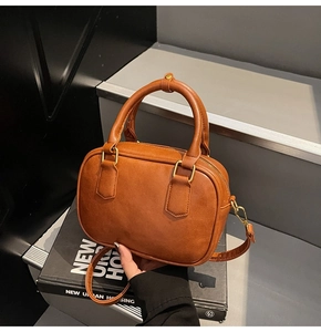 Detailed macro view of the brown faux leather texture and golden metal buckle on the bag