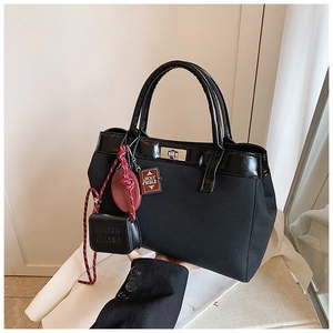 Detailed view of matte black handbag with metal twist lock and unique charms