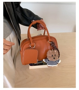 Detail of a brown leather handbag with a cute bear pendant and detachable mini card pouch