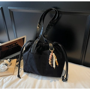 Detail of black suede drawstring tote bag with decorative colorful beads and side pocket