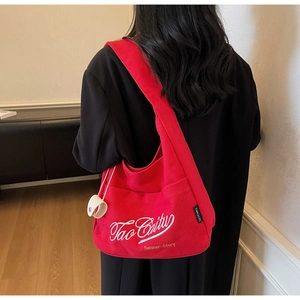 Detailed back view of a large red canvas bucket bag with white embroidery on a black coat