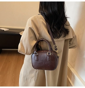 Detailed back view of a retro dark brown crossbody bag on a classic khaki trench coat