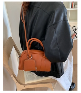 Detailed side view of orange leather Boston bag with attached small zipper pouch