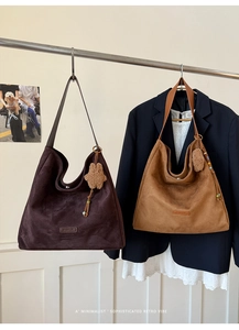 Detail of suede tote bags featuring brand label and decorative star pendant accessory