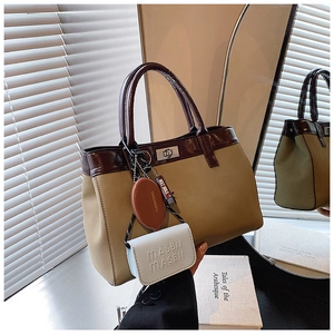 Detail of canvas handbag with leather trim, silver twist lock and fashion charms