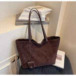 Detail of dark brown suede tote bag with minimalist shoulder straps and vintage texture