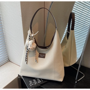 Détail du sac hobo en toile avec poignées en cuir marron et pendentif ours décoratif