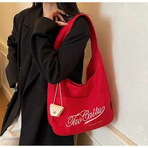 Close-up of red canvas tote bag with white embroidery and mini cream hanging pouch