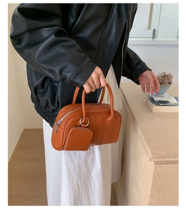 Detail of tan leather crossbody bag with a mini coin purse worn with a leather jacket