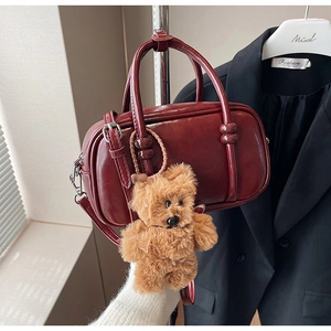 Detail of vintage burgundy patent leather bag with a cute brown plush bear charm