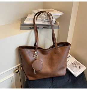 Detail of dark brown tote bag in pebbled PU leather with matching round coin pouch charm