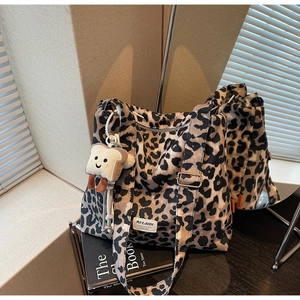 Detail of leopard print tote bag with plush toast charm on a wooden table