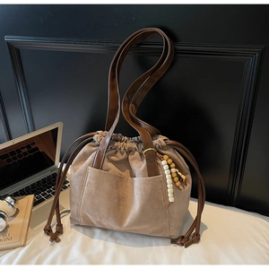 Detailed shot of brown suede bucket bag with leather drawstring and beaded charm