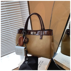 Close-up of matte leather tote with metal twist lock and decorative mini-bag charms