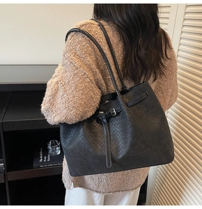 Model side view showing black woven leather tote bag with elegant thin shoulder straps