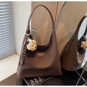 Détail du sac cabas en toile marron avec anses en cuir et breloque ours