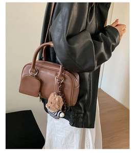Detail of dark brown leather Boston bag with zip pocket and cute bear charm pendant
