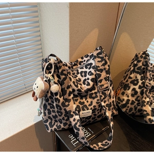 Detail of leopard print tote bag with plush toast charm and adjustable shoulder strap