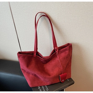Detail of burgundy faux suede tote bag featuring slim shoulder straps and matte finish
