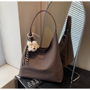 Détail du sac hobo avec écusson en cuir et charmant porte-clés ours en peluche