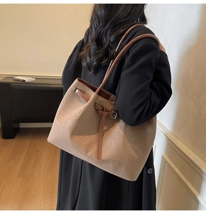 Detail of woven leather tote bag texture and side strap on brown oversized shoulder bag