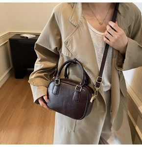 Detail view of dark brown leather Boston bag with gold hardware and shoulder strap