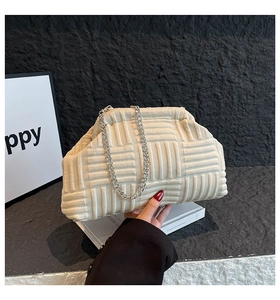 Détail d'un sac à main beige en tricot avec grosse chaîne argentée et motif tissé