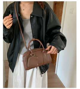 Brown leather crossbody bag with top handles and a small hanging coin purse accessory