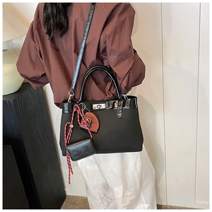 Detail of black nylon tote bag with polished patent leather trim and silver metal twist lock