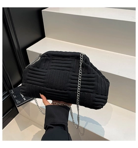 Close-up of black knitted shell bag with woven texture and silver metal chain strap