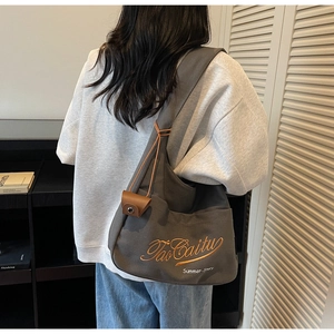 Detailed shot of grey canvas tote bag with orange embroidery and leather clasp detail