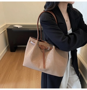 Detail of woven texture and brown leather strap with silver buckle on large tote bag