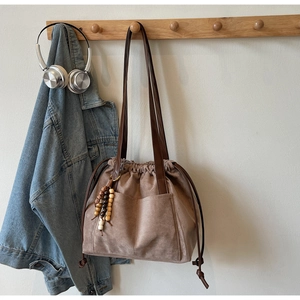 Detail of vintage suede bucket bag with drawstring closure and wood bead charm