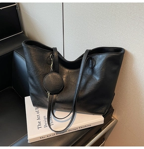 Detail of black faux leather tote with pleated texture and matching mini round pouch