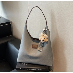 Détail d'un grand sac cabas en toile avec garniture en cuir marron et breloque en peluche
