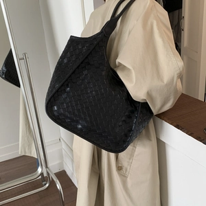 Detailed view of black woven leather tote bag texture with large capacity and shoulder strap