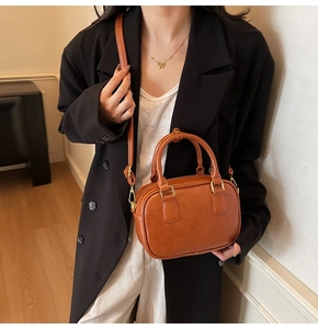 Detailed close-up of brown vintage leather crossbody bag texture and gold hardware