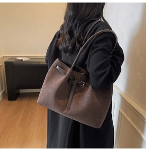 Model wearing a retro deep brown pleated tote bag with sleek leather straps in a minimal room