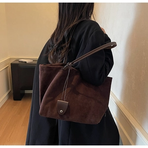Detail of dark brown faux suede tote bag with knot strap detail and matte leather finish