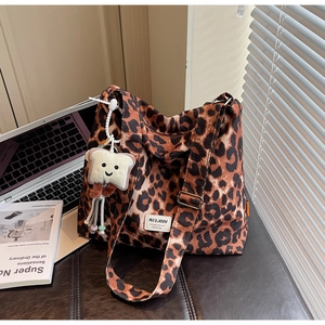 Detail of leopard print tote bag with plush toast pendant on modern desk setup