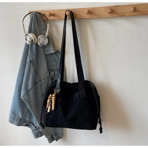 Detail of black canvas tote bag with leather strap and colorful ethnic wood beads