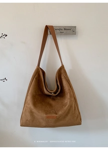 Detail of a brown suede minimalist tote bag with PANTOR label hanging on a wall hook
