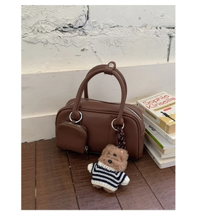 Detail view of vintage brown leather handbag with small front pocket and bear charm