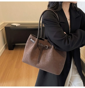Brown vintage tote bag with pleated texture and metal buckle shown on a model's shoulder