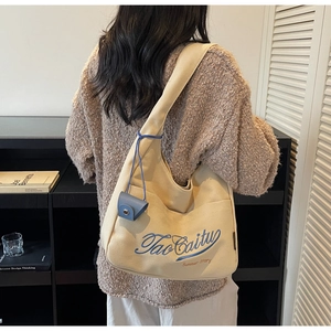 Detail of beige canvas tote with blue embroidery and matching mini hanging coin purse